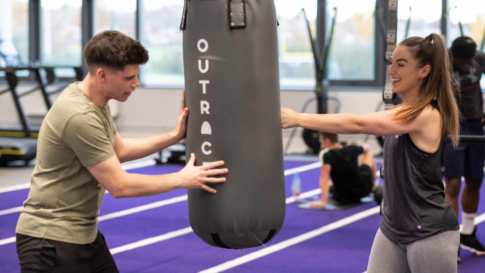 Person holding punching bag for other person in a gym