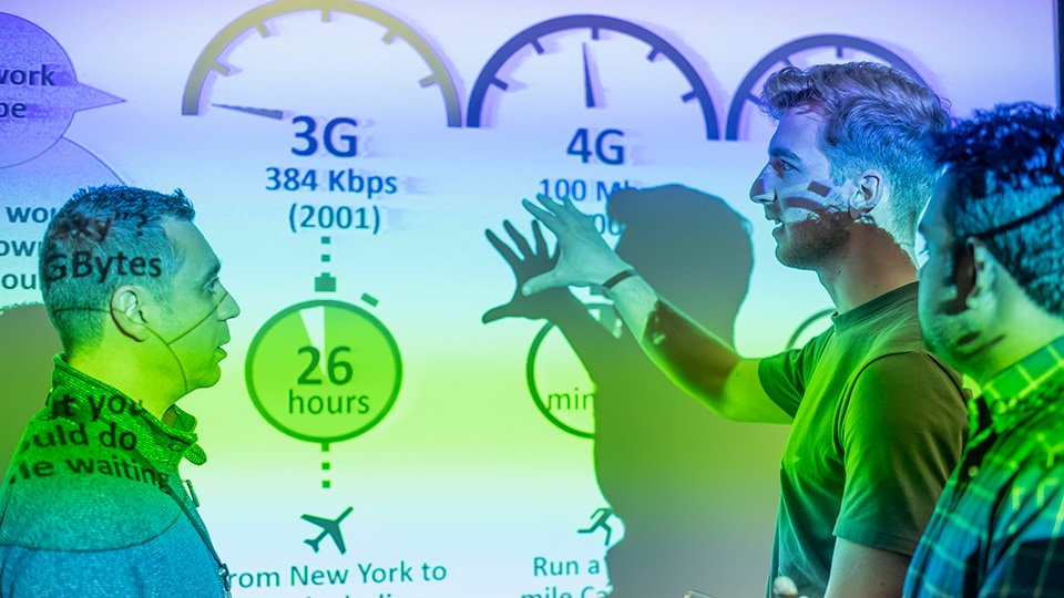 Three people discussing information being projected onto a wall