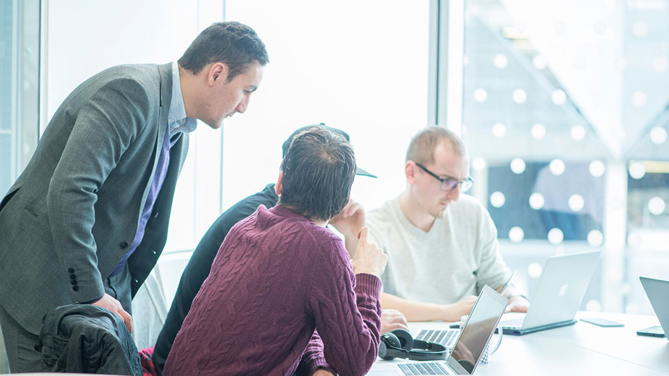 A group of people sat at a table looking at computer screens