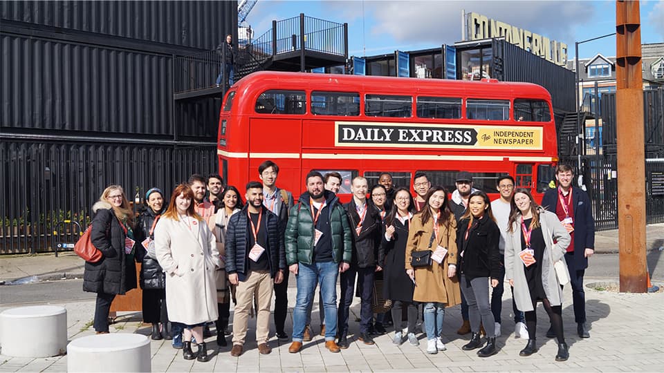Students standing in front of a red London bus