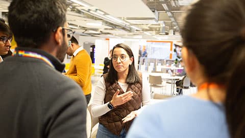 a group of three people standing talking, one faces the camera