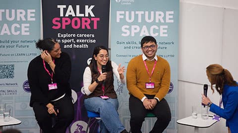 three people sitting in front of banners and one person asking questions