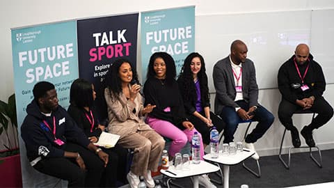 a group of people sitting on the stage with banners behind them