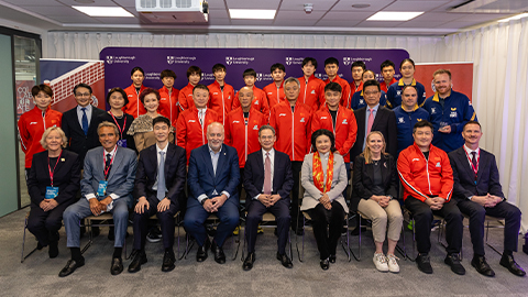 Team China and Chinese embassy diplomats sat taking a group picture