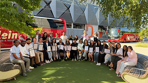 Students and staff smiling at camera holding up award certificates outside