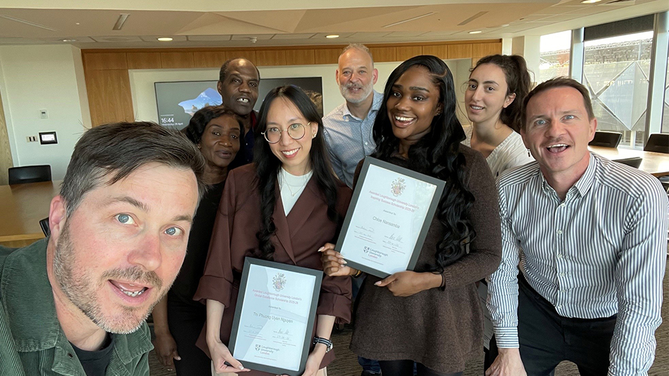 Students and staff smiling at camera holding up scholarship certificates