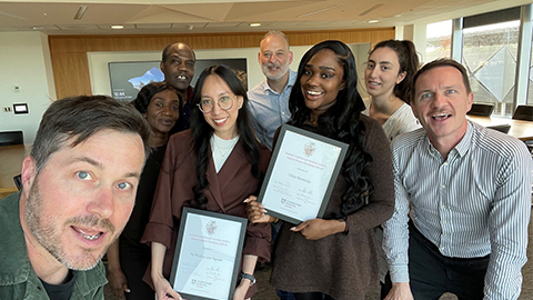 Students and staff smiling at camera holding up scholarship certificates