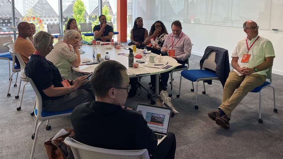 Advisory Group sitting around a meeting room table watching a presentation