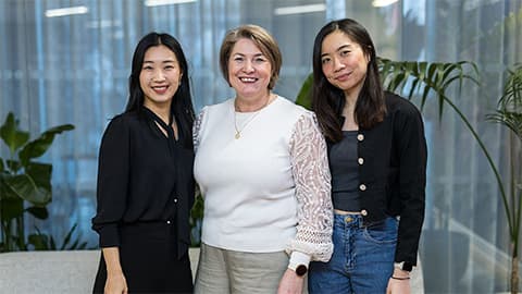 Three women stood together smiling at the camera