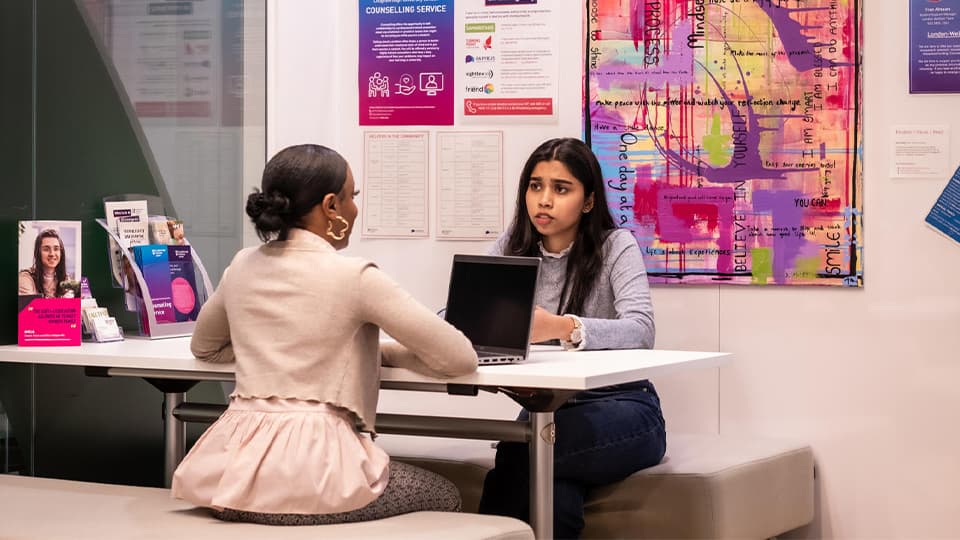 Two people sitting and talking opposite each other at a desk